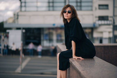 Portrait of young woman wearing sunglasses in city