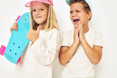 Brother crying while standing by sister holding skateboard