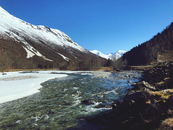Scenic view of snowcapped mountains against clear blue sky