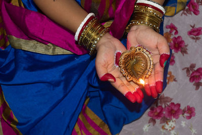 Hands of an indian woman holding diya or pradip on diwali .