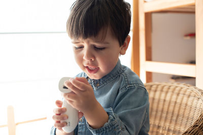 Boy holding mobile phone at home