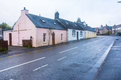 Road by buildings in city against sky