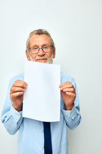 Senior man showing paper against white background