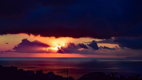 Scenic view of sea against dramatic sky during sunset