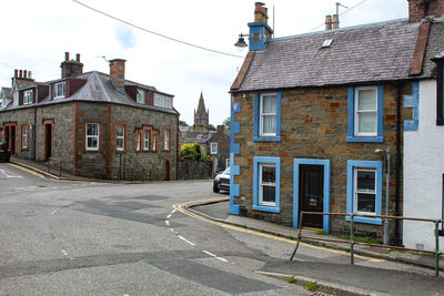 Road by buildings against sky in city