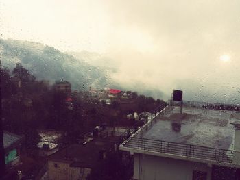 View of city through water drops on rainy day