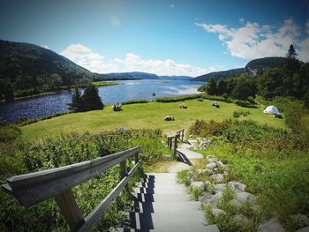 Steps on field by river against sky