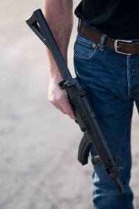 Cropped image of man with rifle standing on ground