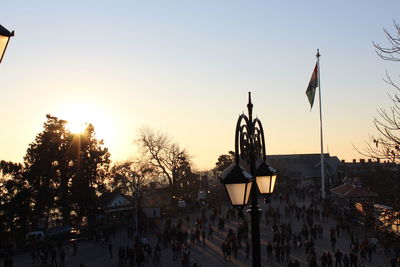 People on street against sky during sunset