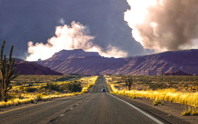 Road leading towards mountains against sky