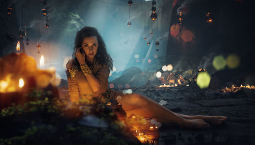 Woman sitting on illuminated fire at night