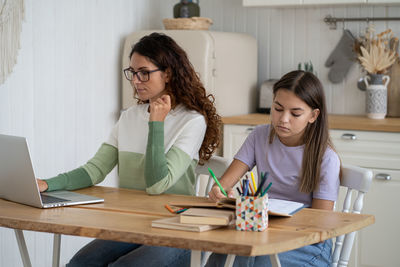 Female friends using laptop at home