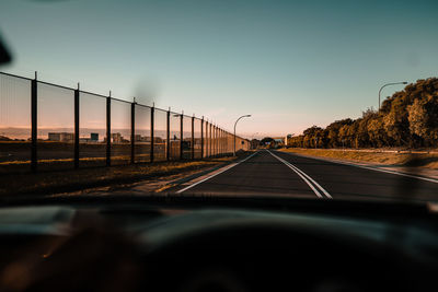 Road seen through car windshield during sunset