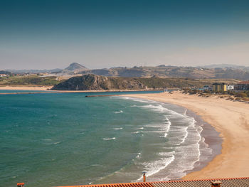 Scenic view of sea and mountains against blue sky