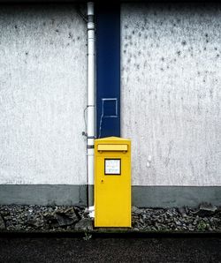 Yellow mailbox against wall