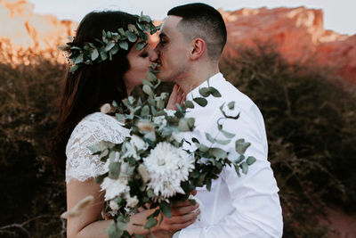 Couple kissing on white flowering plants