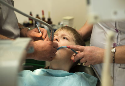 Midsection of dentist examining boy at hospital