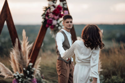 Friends standing on land against sky during sunset