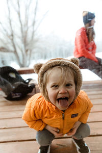 Three year old smiling girl looks through window with tongue out