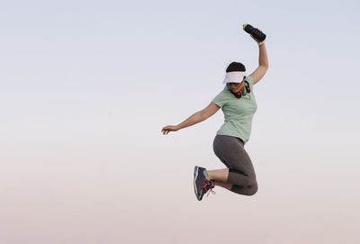 Full length of man jumping against clear sky