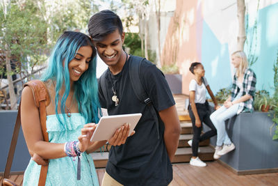 Smiling friends looking at digital tablet