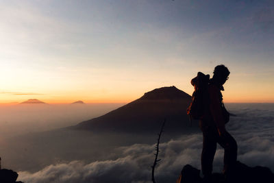 Man standing on mountain against sky during sunset