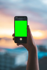 Low section of person holding mobile phone against sea
