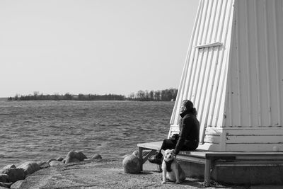 Woman sitting on shore against sky
