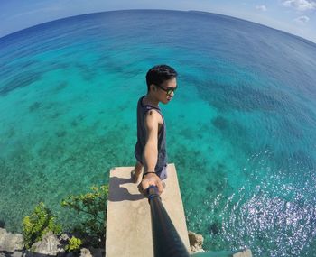 Young man standing in sea against sky