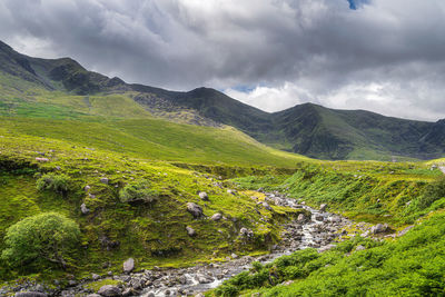 Scenic view of stream amidst mountains against sky