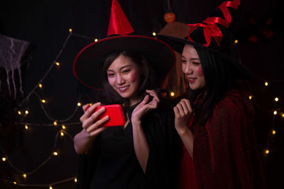 Young woman holding smart phone while standing at night