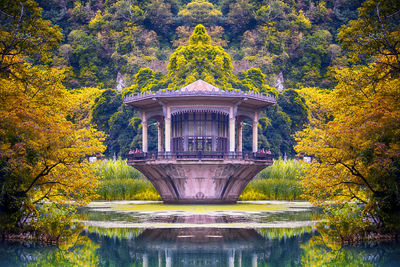 Built structure by lake against trees during autumn