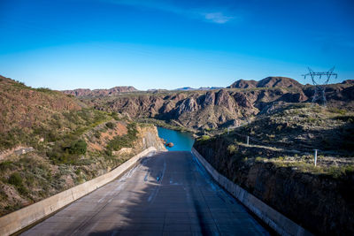 Road amidst mountains against clear blue sky