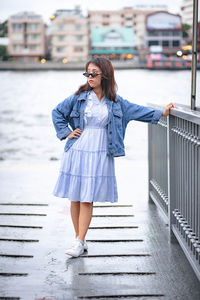 Woman looking away while standing by railing against river 