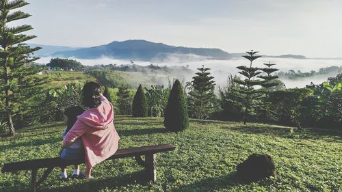 Rear view of woman looking at trees against sky