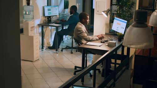 Rear view of man using mobile phone while standing in office