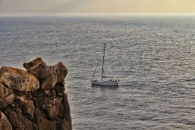 Sailboats on rock in sea against sky