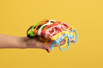 Cropped hand of woman holding toy against yellow background