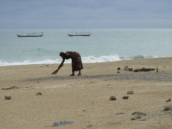 Rear view of man on beach against sky