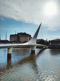 Bridge over river against sky in city