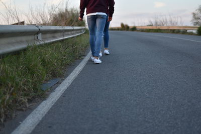 Low section of friends walking on roadside