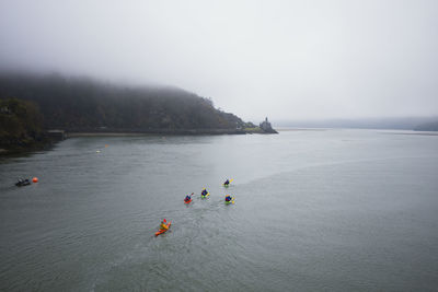 A party of kayakers paddling up the estuary at low tide on a misty day in barmouth, north wales
