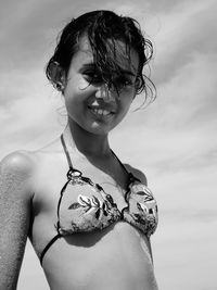 Portrait of smiling girl in bikini top against sky