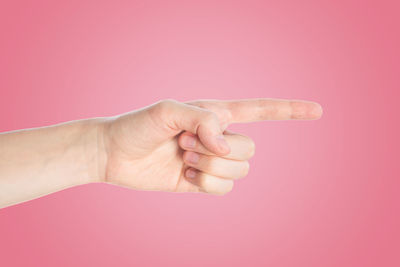 Close-up of hand holding light bulb over pink background