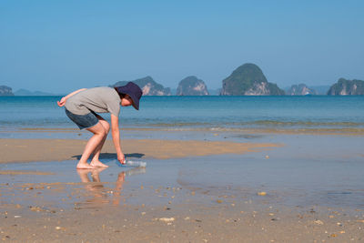 Young woman collecting used plastic bottle from the beach to save environment and marine ecosystem