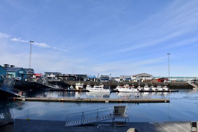 Boats moored at harbor against blue sky