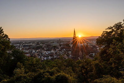 Trees and buildings against sky during sunset