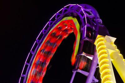 Blurred motion of illuminated rollercoaster at night