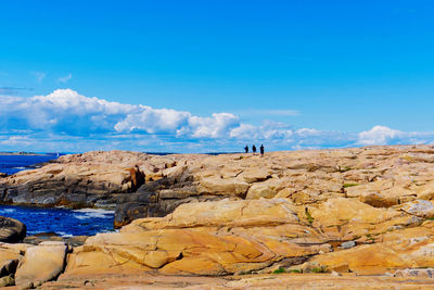 Three explorers hike along the slabs of rock along the textured coast of asmaløy in hvaler, norway 