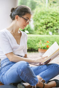 Young woman looking away while sitting outdoors